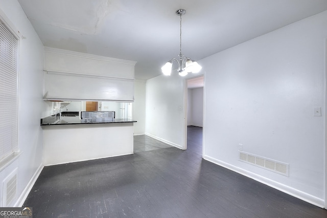 707 E Spring St, Monroe, GA 30655 - kitchen with dark countertops, a chandelier, a peninsula, dark wood-style floors, and baseboards