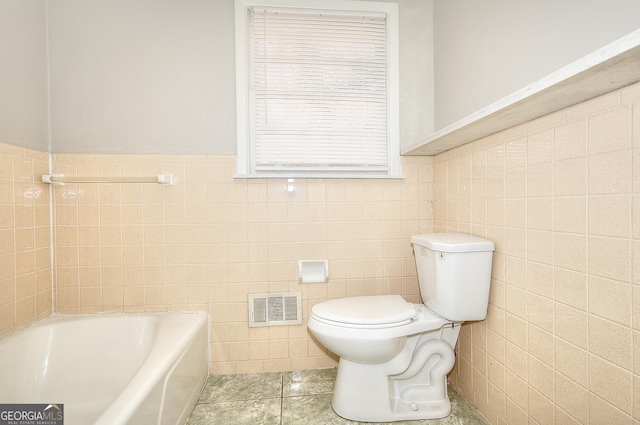 707 E Spring St, Monroe, GA 30655 - bathroom with tile walls, toilet, a bathtub, tile patterned floors, and a wainscoted wall