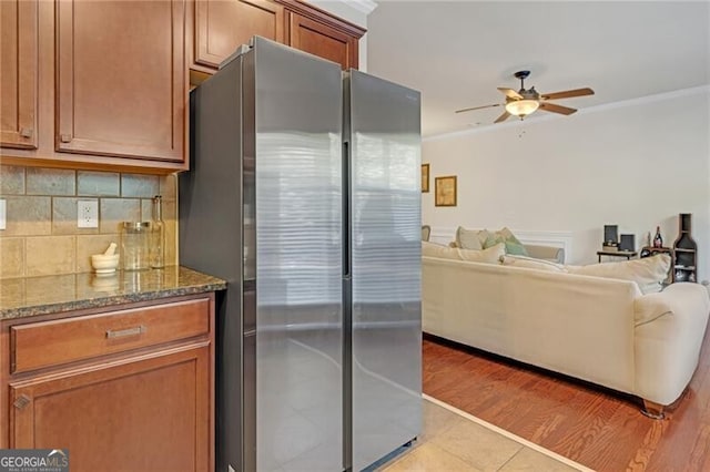 5711 Keys Way, Lithonia, GA 30058 - kitchen with freestanding refrigerator, ceiling fan, decorative backsplash, dark stone countertops, and brown cabinetry