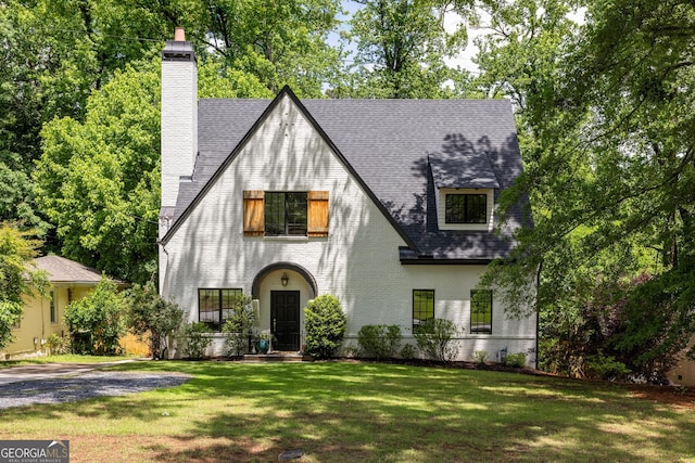 2554 Saint Patrick St SE, Atlanta, GA 30317 - tudor home with a front yard, a chimney, roof with shingles, and brick siding