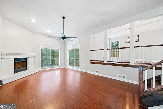 175 River Run, Roswell, GA 30075 - unfurnished living room with ceiling fan, wood finished floors, a textured ceiling, a brick fireplace, and baseboards