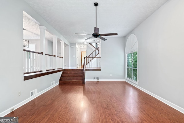 175 River Run, Roswell, GA 30075 - unfurnished living room featuring wood finished floors, a ceiling fan, baseboards, stairs, and a textured ceiling