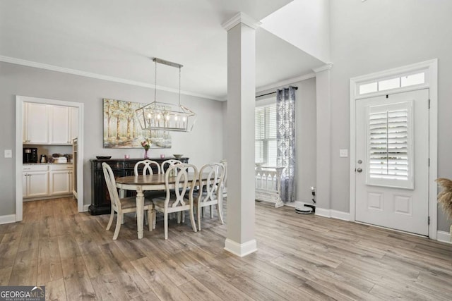 dining space with ornamental molding, light wood-style flooring, a chandelier, and baseboards
