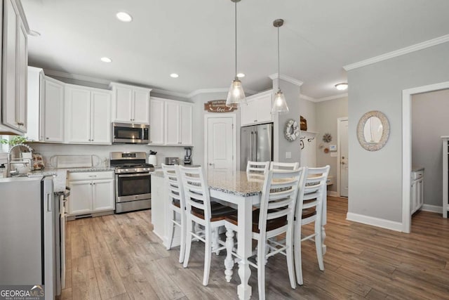 kitchen featuring stainless steel appliances, white cabinets, light wood-type flooring, crown molding, and recessed lighting