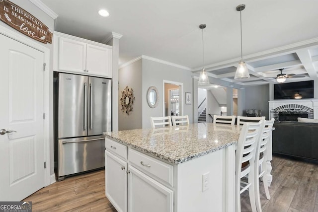 kitchen featuring high end fridge, recessed lighting, light wood-style flooring, a breakfast bar, and crown molding