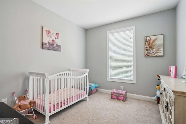 bedroom with a nursery area, carpet flooring, and baseboards