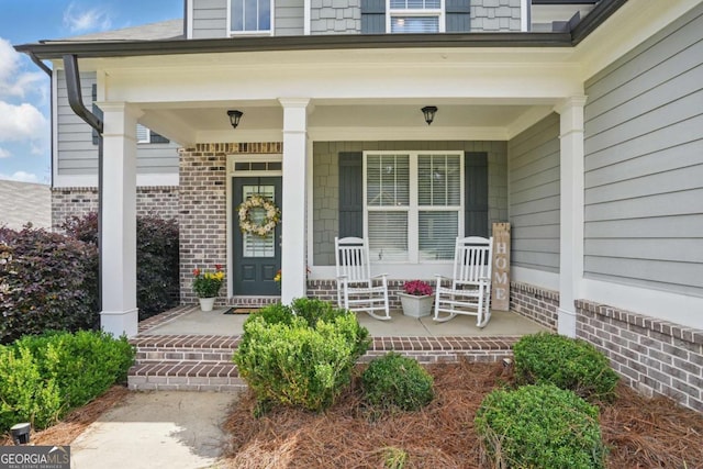 property entrance featuring covered porch and brick siding