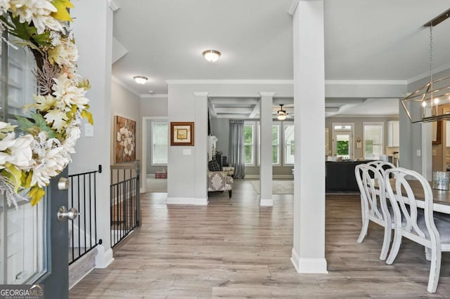 foyer entrance featuring crown molding, wood finished floors, a ceiling fan, baseboards, and decorative columns