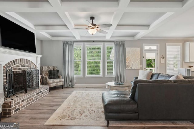 living room with a brick fireplace, wood finished floors, a ceiling fan, coffered ceiling, and beamed ceiling