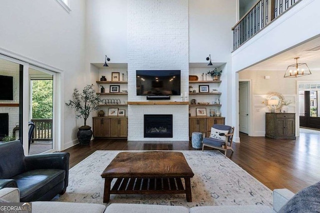 4992 Concert Ln, Marietta, GA 30066 - living room featuring a fireplace, a towering ceiling, wood finished floors, a chandelier, and baseboards
