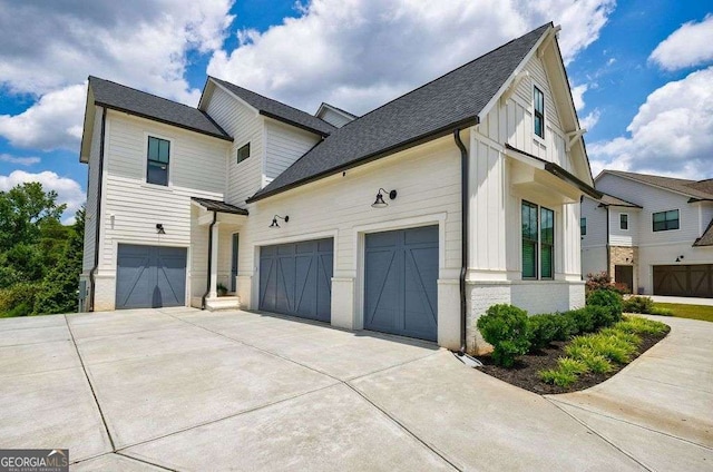 4992 Concert Ln, Marietta, GA 30066 - view of side of property featuring board and batten siding, driveway, a garage, roof with shingles, and brick siding