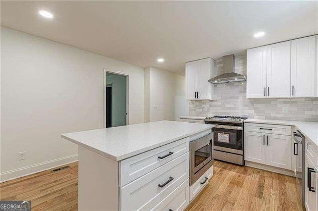 418 Mockingbird Ln, Smyrna, GA 30082 - kitchen featuring wall chimney exhaust hood, appliances with stainless steel finishes, light wood-style flooring, light countertops, and recessed lighting