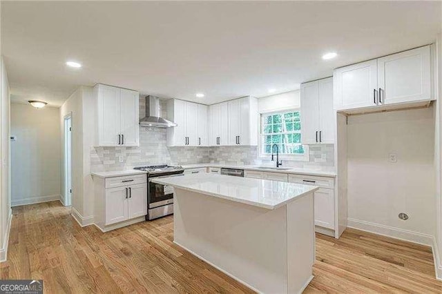 418 Mockingbird Ln, Smyrna, GA 30082 - kitchen featuring stainless steel appliances, wall chimney range hood, a sink, light wood-style floors, and white cabinets