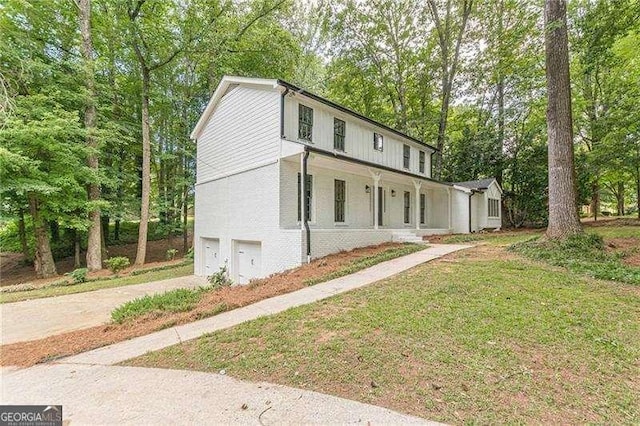 418 Mockingbird Ln, Smyrna, GA 30082 - modern farmhouse with an attached garage, concrete driveway, a porch, a front lawn, and view of wooded area