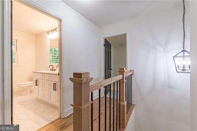 418 Mockingbird Ln, Smyrna, GA 30082 - hallway featuring an upstairs landing, a chandelier, a sink, and light marble finish flooring