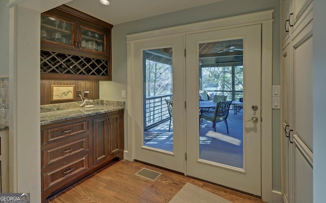 entryway with wet bar and light wood-style flooring