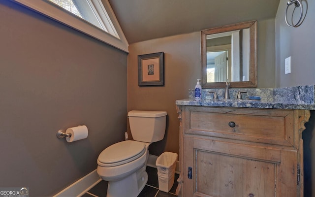 half bath with lofted ceiling, toilet, baseboards, and vanity