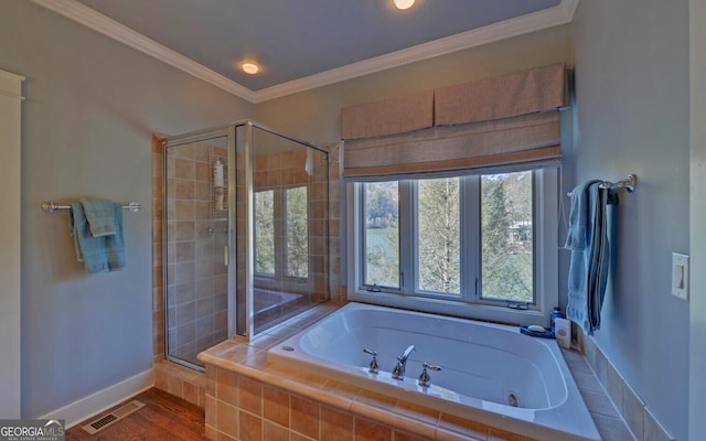 bathroom with a stall shower, a tub with jets, crown molding, baseboards, and wood finished floors