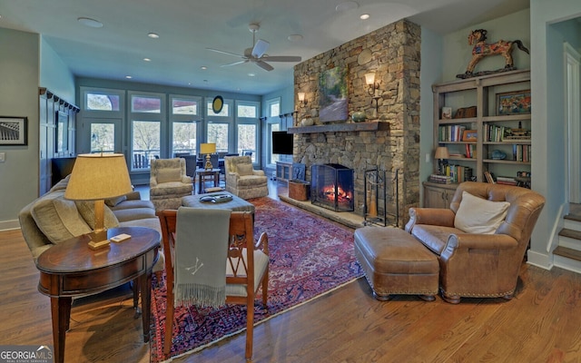 living area featuring a stone fireplace, ceiling fan, plenty of natural light, wood finished floors, and recessed lighting