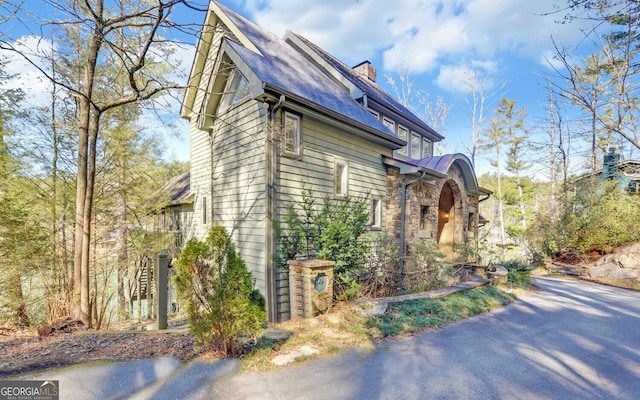 view of property exterior featuring a chimney and stone siding