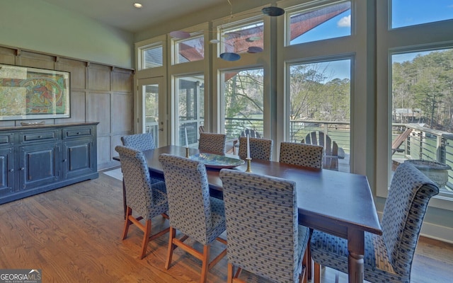 dining room with wood finished floors, recessed lighting, and a high ceiling