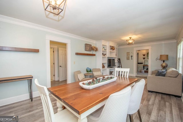 dining room featuring a chandelier, ornamental molding, light wood-style flooring, and baseboards