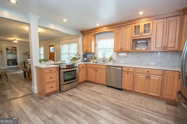 kitchen featuring stainless steel appliances, a sink, light countertops, light wood-style flooring, and recessed lighting