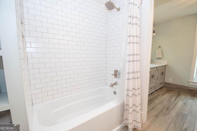 bathroom with wood finished floors, shower / tub combo, vanity, and baseboards