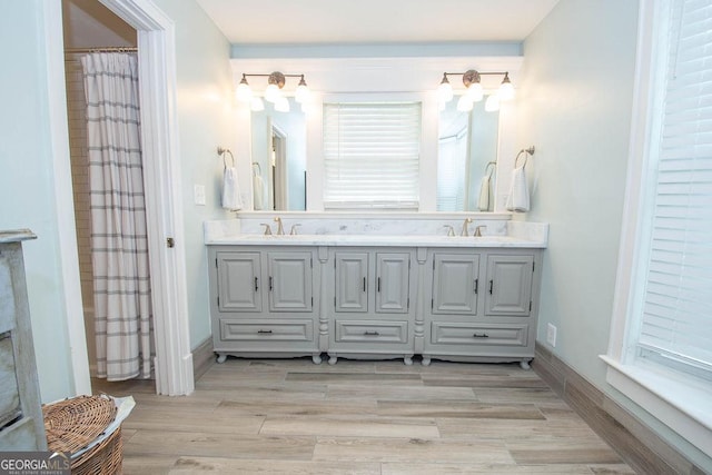 bathroom with double vanity, wood finished floors, and baseboards