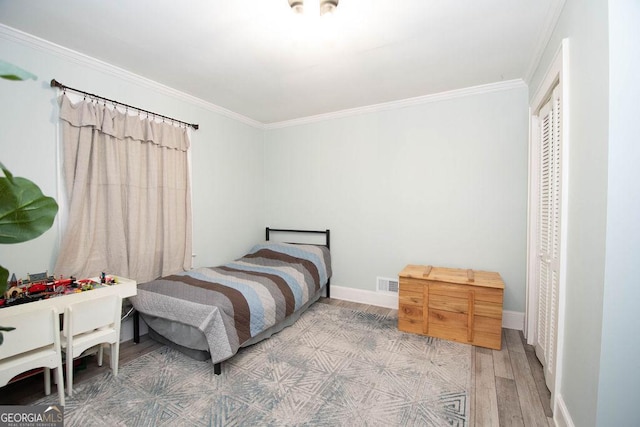 bedroom featuring light wood-style flooring, crown molding, baseboards, and a closet