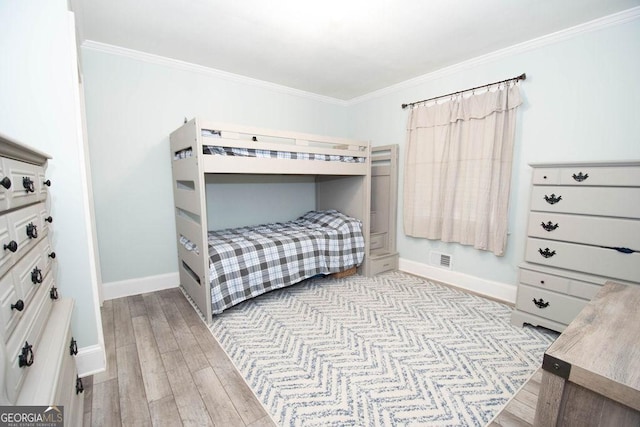 bedroom with crown molding, wood finished floors, and baseboards