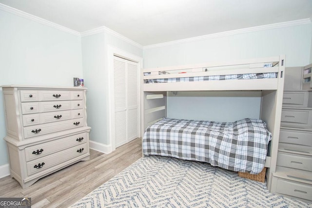 bedroom featuring ornamental molding, light wood-type flooring, a closet, and baseboards