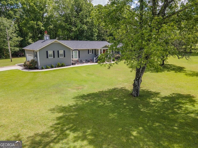view of front of home with a front yard, a chimney, and an attached garage