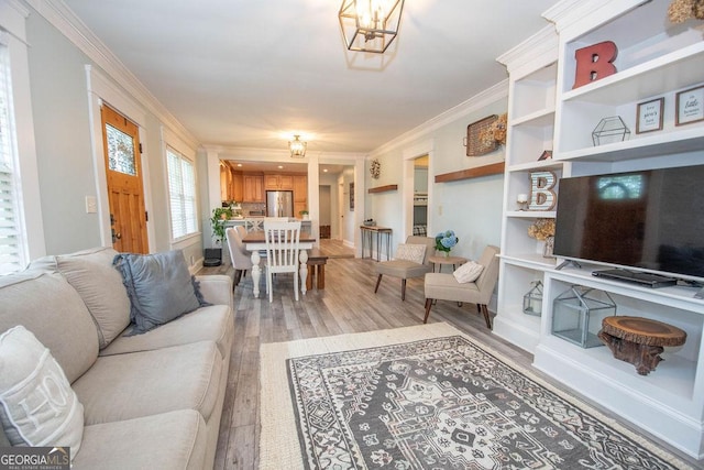 living area featuring light wood-style floors, ornamental molding, and a chandelier