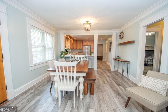 dining space with light wood finished floors, crown molding, and baseboards