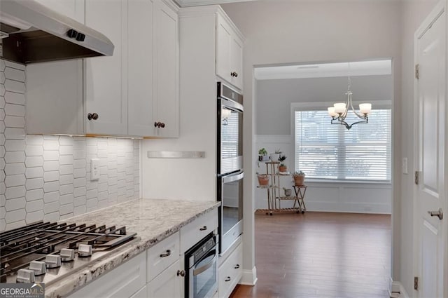 541 Glen Abbey Cir, Mableton, GA 30126 - kitchen with under cabinet range hood, stainless steel appliances, decorative backsplash, a chandelier, and white cabinets