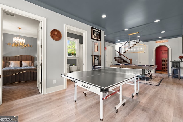 rec room featuring light wood finished floors, baseboards, arched walkways, recessed lighting, and crown molding