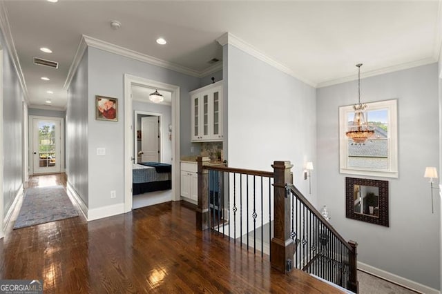 corridor with an upstairs landing, dark wood-style flooring, baseboards, a chandelier, and crown molding
