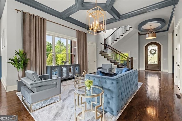 living room with wood finished floors, baseboards, coffered ceiling, a chandelier, and stairs