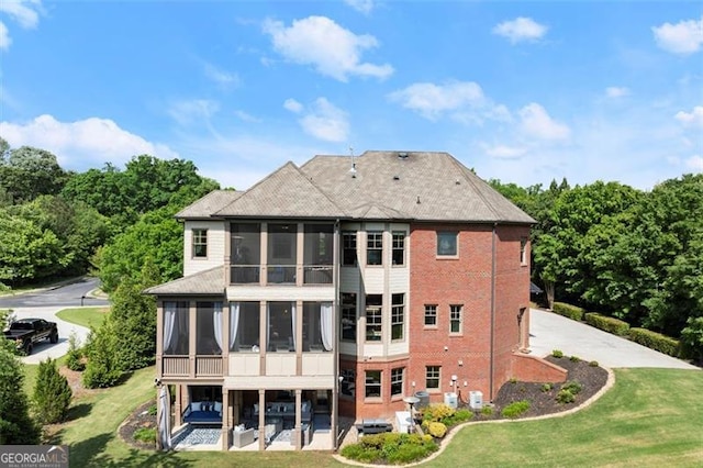 back of property featuring a sunroom, a yard, a patio area, and brick siding