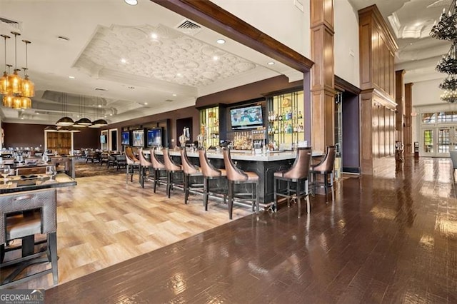 community bar area featuring a tray ceiling, ornamental molding, a chandelier, wood finished floors, and recessed lighting