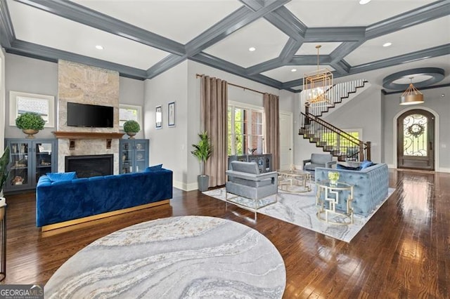 living room with a fireplace, stairs, baseboards, coffered ceiling, and ornamental molding