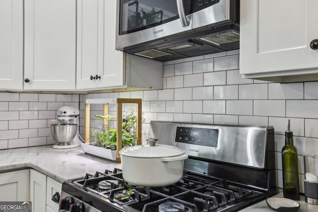 1211 Mortimer Pl SE, Atlanta, GA 30317 - kitchen featuring stainless steel appliances, decorative backsplash, white cabinets, and light stone counters