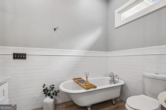 1211 Mortimer Pl SE, Atlanta, GA 30317 - bathroom featuring tile walls, wood finished floors, a freestanding tub, toilet, and wainscoting