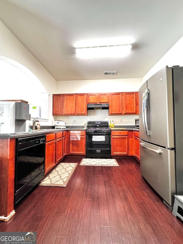 kitchen with black appliances, under cabinet range hood, a sink, and dark wood finished floors