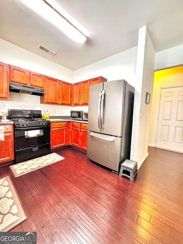 kitchen with appliances with stainless steel finishes, under cabinet range hood, dark wood-style flooring, and brown cabinetry