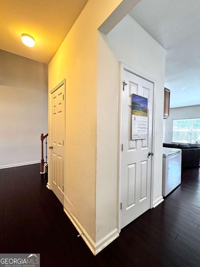 hall featuring dark wood-style flooring and baseboards