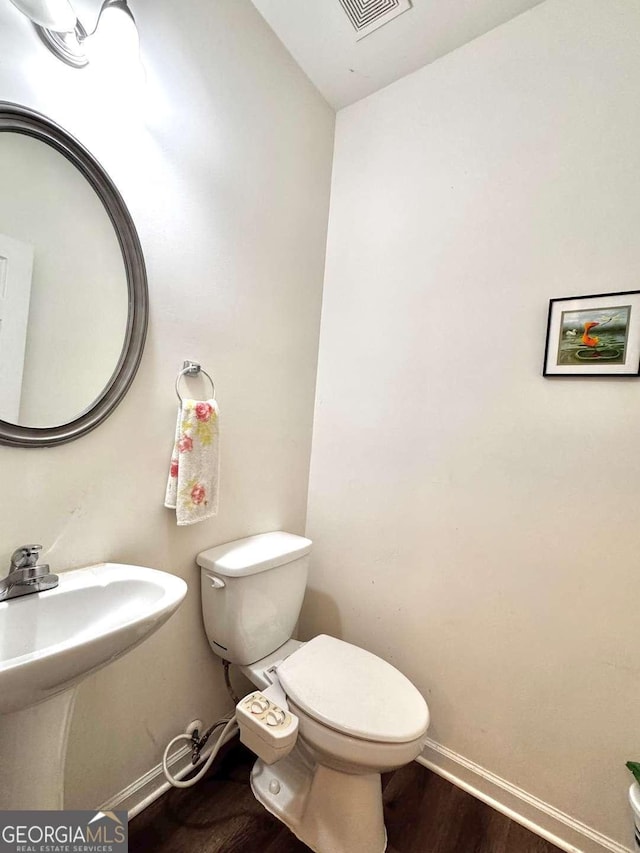 bathroom with toilet, wood finished floors, and baseboards