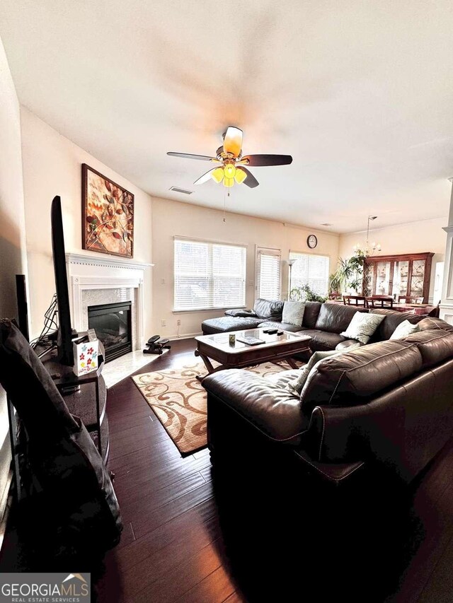 living area with ceiling fan, a premium fireplace, and dark wood-style flooring