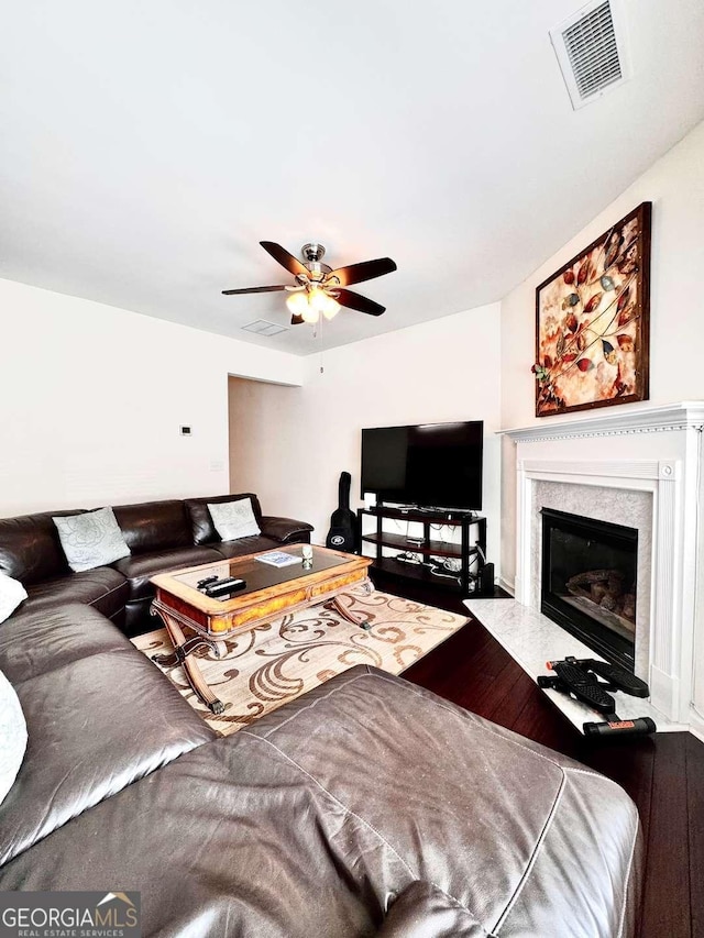 living area with a ceiling fan, wood finished floors, and a fireplace